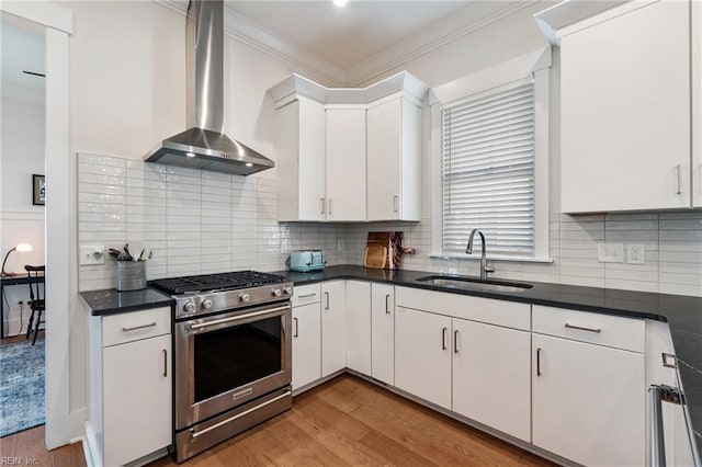 kitchen with white cabinetry, sink, wall chimney range hood, ornamental molding, and stainless steel range with gas stovetop