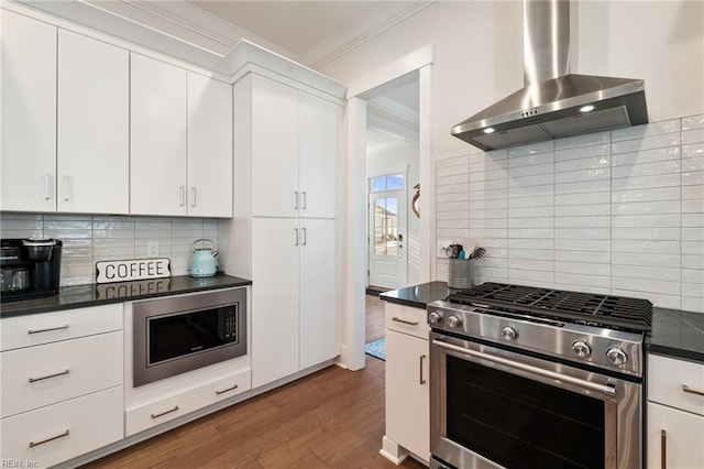 kitchen featuring stainless steel appliances, dark hardwood / wood-style floors, ornamental molding, white cabinets, and wall chimney exhaust hood