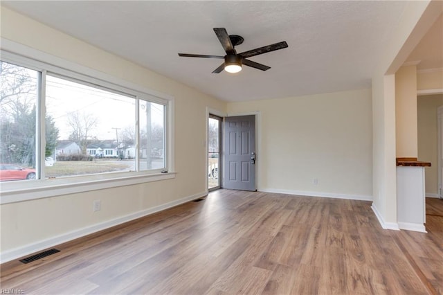 empty room with plenty of natural light, ceiling fan, and light hardwood / wood-style flooring