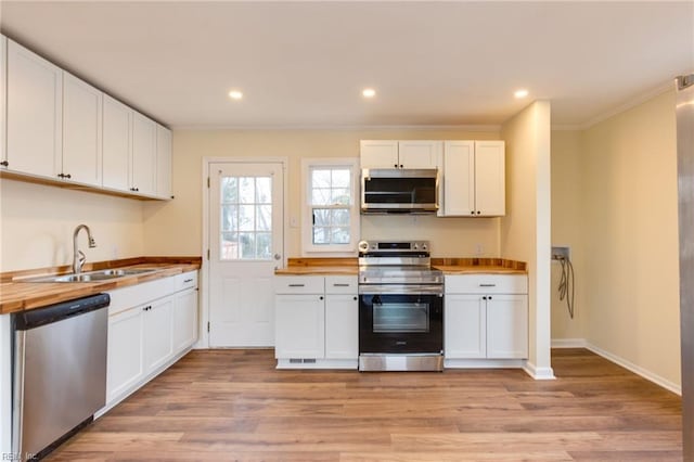 kitchen with appliances with stainless steel finishes, white cabinets, and wood counters