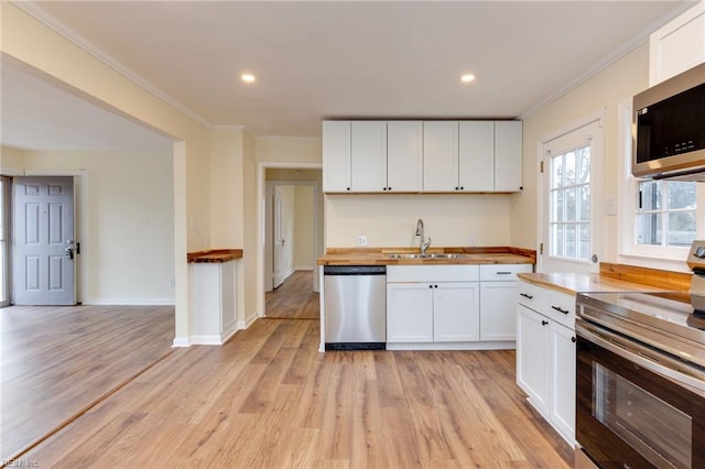 kitchen with white cabinetry, stainless steel appliances, and butcher block countertops