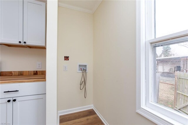 laundry room with crown molding, hookup for a washing machine, cabinets, and hardwood / wood-style flooring