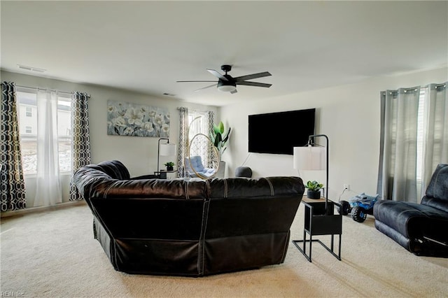 living room featuring ceiling fan, light colored carpet, and a healthy amount of sunlight