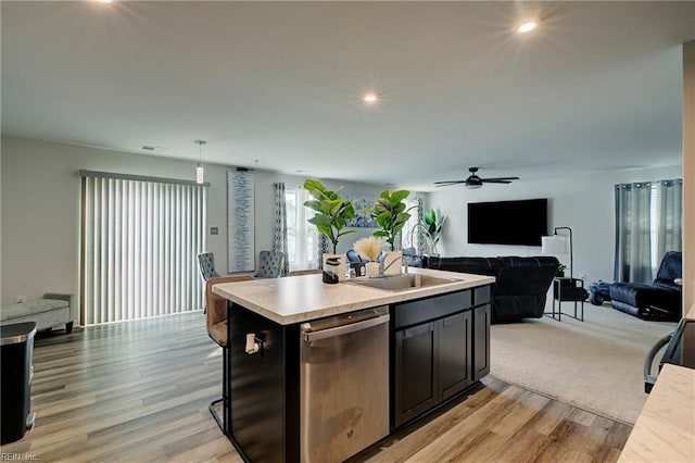 kitchen with dishwasher, sink, hanging light fixtures, light hardwood / wood-style floors, and a center island with sink