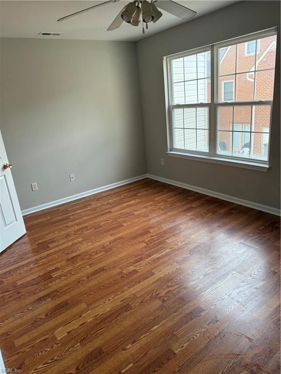 empty room with dark hardwood / wood-style floors and ceiling fan