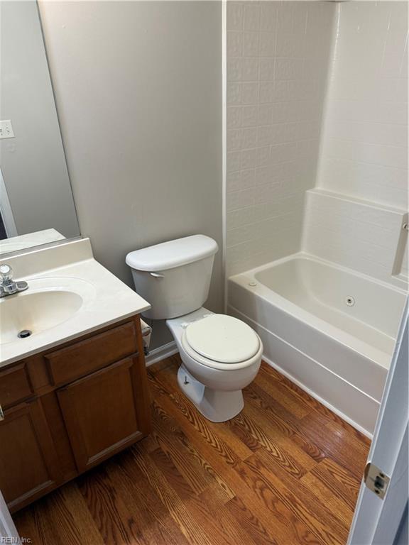 full bathroom with vanity, toilet, hardwood / wood-style floors, and shower / tub combination