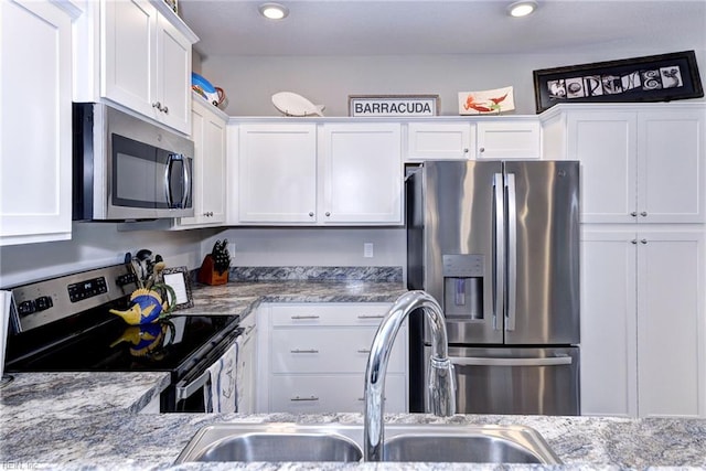 kitchen with stainless steel appliances, white cabinetry, and sink