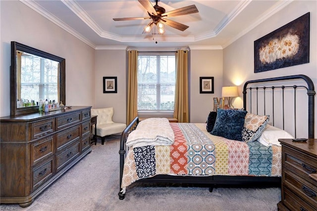 bedroom with crown molding, light colored carpet, ceiling fan, and a tray ceiling