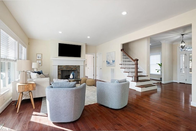 living room featuring a stone fireplace, a chandelier, and dark hardwood / wood-style flooring