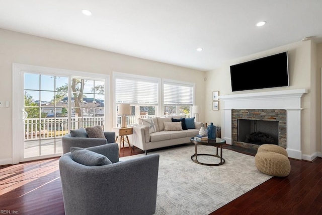 living room with a stone fireplace and dark wood-type flooring