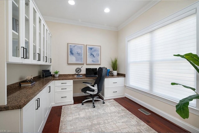 home office featuring dark hardwood / wood-style flooring, built in desk, and ornamental molding