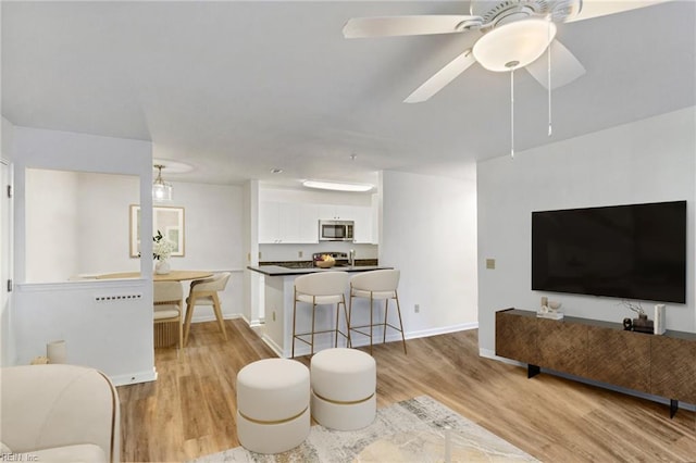 living room with ceiling fan and light wood-type flooring