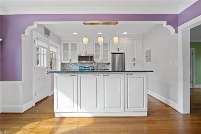 kitchen with white cabinetry, light hardwood / wood-style flooring, pendant lighting, stainless steel appliances, and a kitchen island with sink