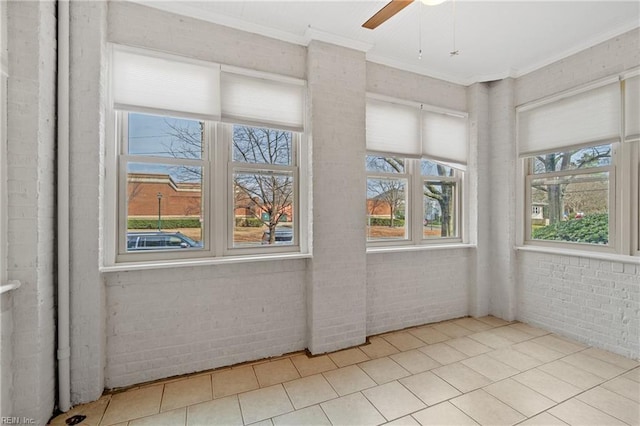 tiled empty room with ornamental molding, brick wall, and ceiling fan