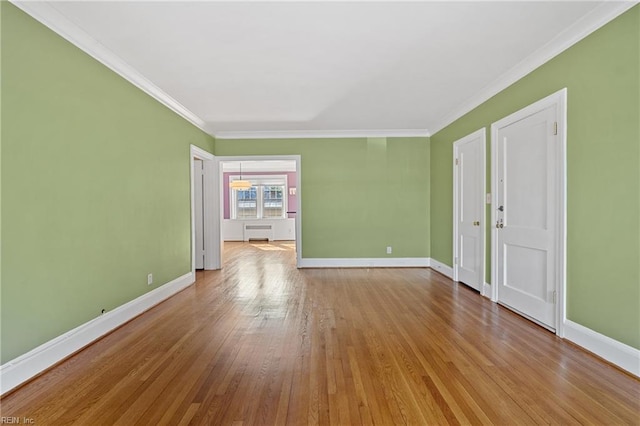 empty room with crown molding, radiator, and light wood-type flooring