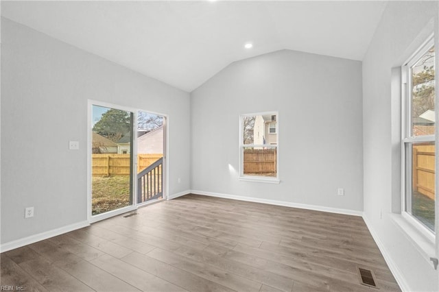 unfurnished room with dark hardwood / wood-style flooring, vaulted ceiling, and a healthy amount of sunlight