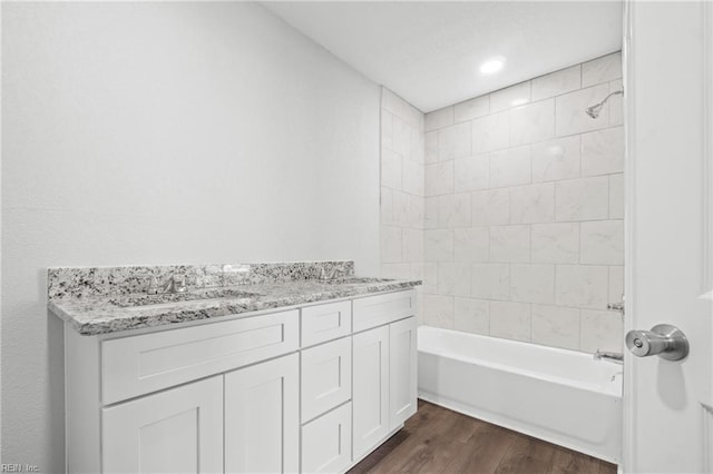 bathroom featuring wood-type flooring, tiled shower / bath combo, and vanity