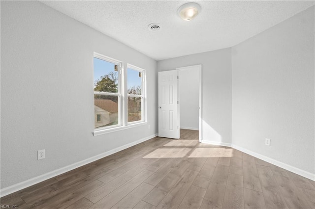 unfurnished room featuring hardwood / wood-style floors and a textured ceiling