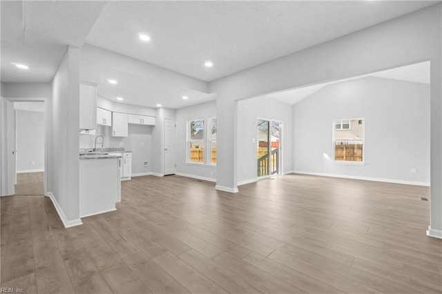 unfurnished living room with sink and light hardwood / wood-style flooring