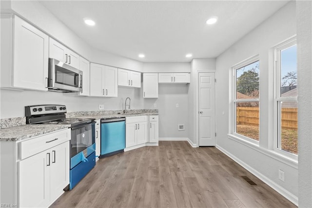 kitchen featuring white cabinetry, appliances with stainless steel finishes, sink, and light stone counters