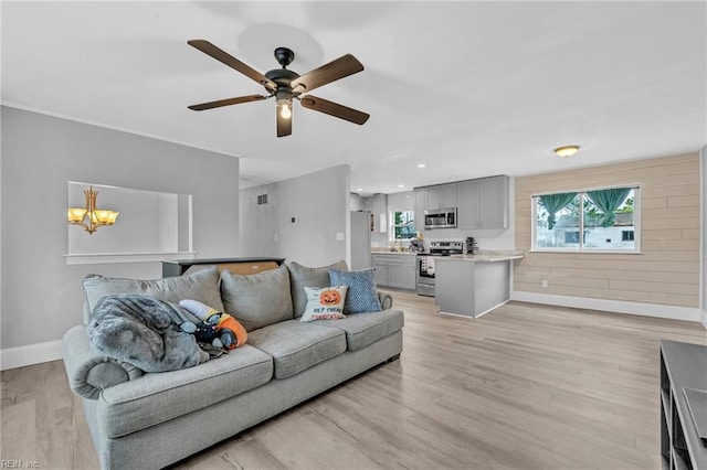 living room featuring ceiling fan with notable chandelier and light hardwood / wood-style floors