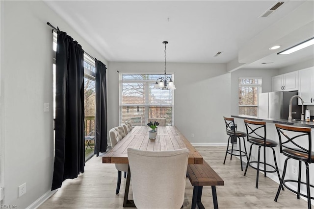 dining room featuring plenty of natural light, sink, a chandelier, and light hardwood / wood-style floors