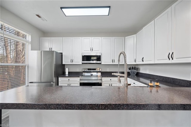 kitchen featuring kitchen peninsula, white cabinets, and appliances with stainless steel finishes