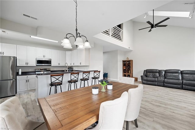 dining area with ceiling fan, high vaulted ceiling, and light wood-type flooring