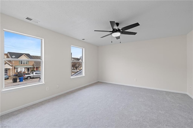 carpeted empty room with ceiling fan and a textured ceiling