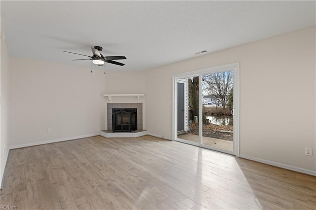 unfurnished living room featuring ceiling fan, a fireplace, and light wood-type flooring