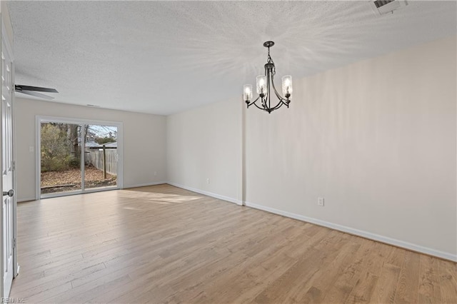 spare room with ceiling fan with notable chandelier, a textured ceiling, and light hardwood / wood-style floors