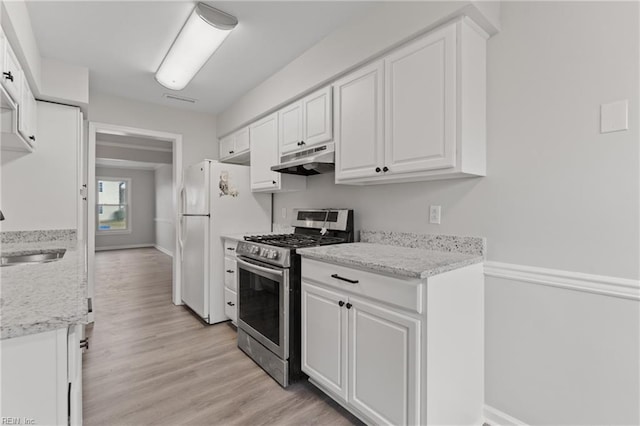 kitchen with sink, white cabinetry, stainless steel range with gas stovetop, light wood-type flooring, and white fridge