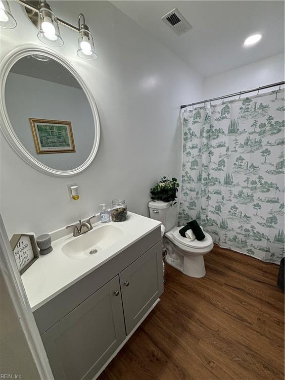 full bath with visible vents, toilet, vanity, wood finished floors, and a shower with curtain
