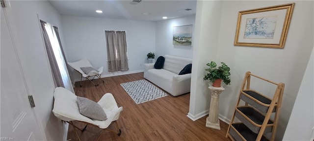 living area with recessed lighting, wood finished floors, visible vents, and baseboards