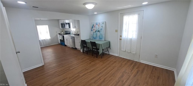 kitchen featuring appliances with stainless steel finishes, visible vents, dark wood finished floors, and baseboards