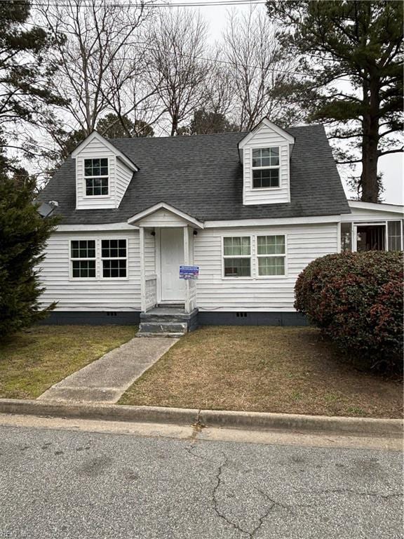 cape cod home with a shingled roof, a front yard, and crawl space