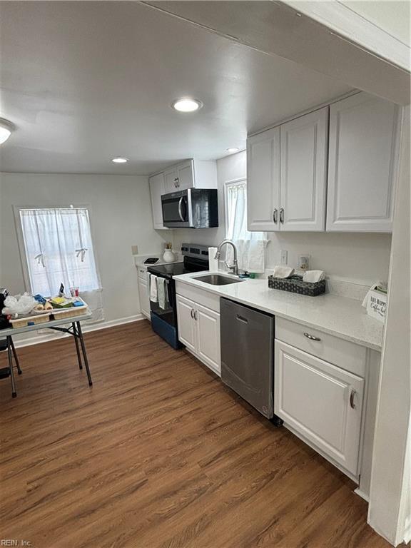 kitchen featuring white cabinets, appliances with stainless steel finishes, dark wood-style flooring, light countertops, and a sink