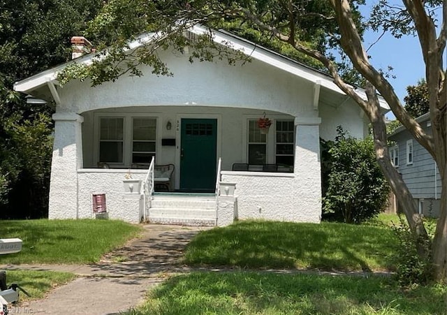 view of front of property featuring covered porch and a front lawn