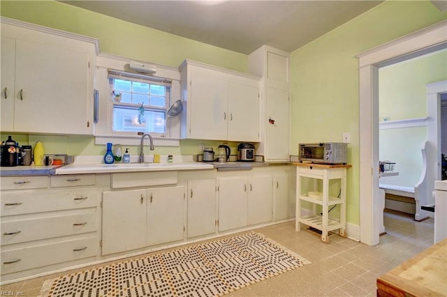 kitchen featuring sink, white cabinets, and light tile patterned flooring