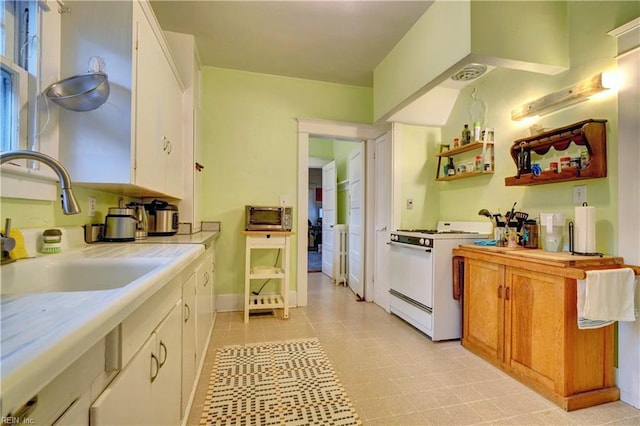 kitchen featuring white cabinetry, white gas range, and sink