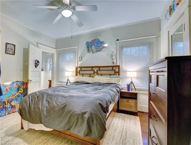 bedroom featuring multiple windows, dark hardwood / wood-style floors, and ceiling fan