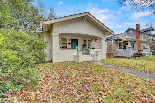 bungalow featuring covered porch and a front lawn