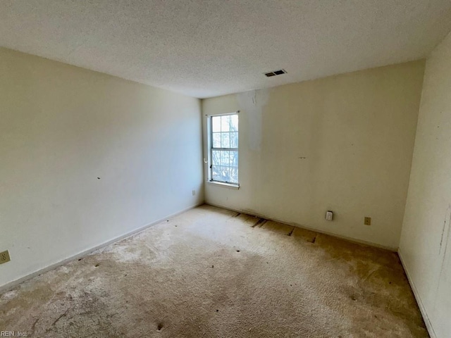 carpeted empty room featuring a textured ceiling