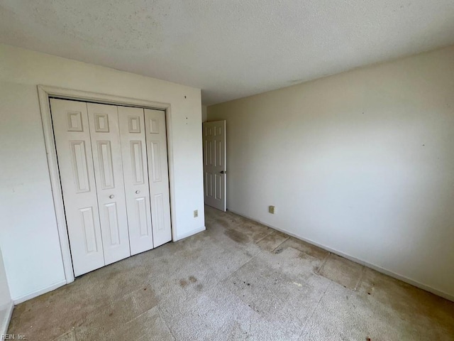 unfurnished bedroom with light colored carpet, a textured ceiling, and a closet