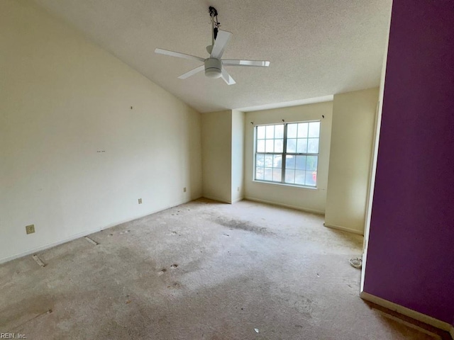 carpeted empty room with ceiling fan, lofted ceiling, and a textured ceiling