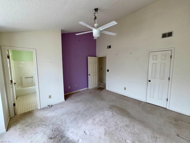 unfurnished bedroom with light colored carpet, connected bathroom, high vaulted ceiling, and a textured ceiling