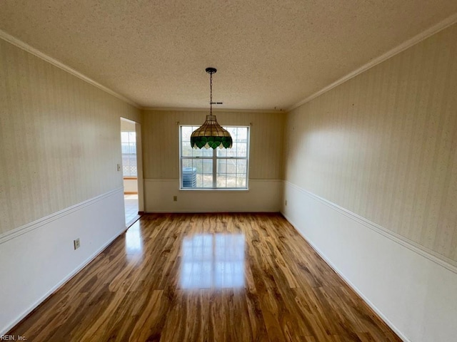 unfurnished dining area featuring ornamental molding, wood-type flooring, and a textured ceiling