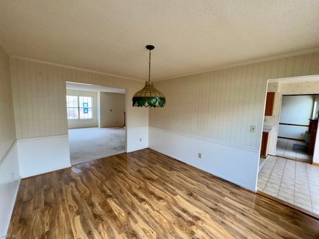 unfurnished dining area featuring hardwood / wood-style flooring, ornamental molding, and a textured ceiling