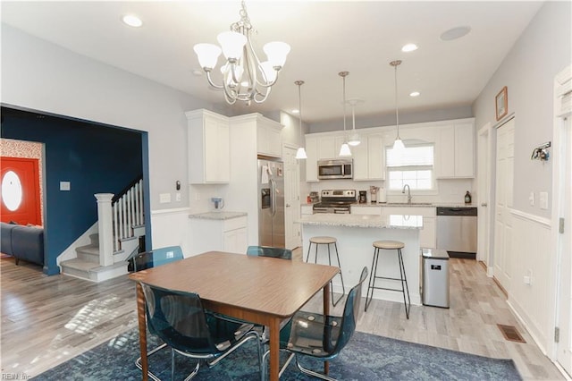 dining space with sink, a chandelier, and light wood-type flooring