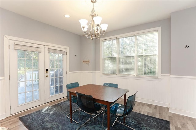 dining space with french doors, a notable chandelier, a healthy amount of sunlight, and hardwood / wood-style flooring